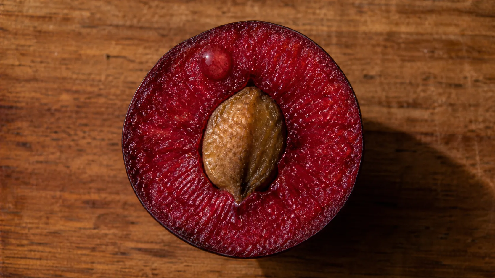 Close-up of a Davidson plum cut open on the bench, showing the deep crimson flesh that VKA Australia reads as a natural colour reference at the Southport site.